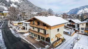 Un bâtiment moderne avec une façade en bois, un balcon et un toit recouvert de neige.