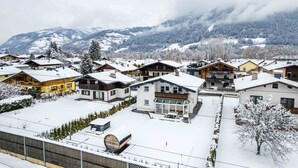 A residential area with snow-covered houses and mountains in the background. - Spa Chalet - Garden Lodge (Zell am See)