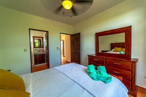 A bedroom with a bed, a wooden dresser, a mirror, and a ceiling fan. - Casa 48· Poolside Relaxing Retreat Near the Beach (Esterillos Este)