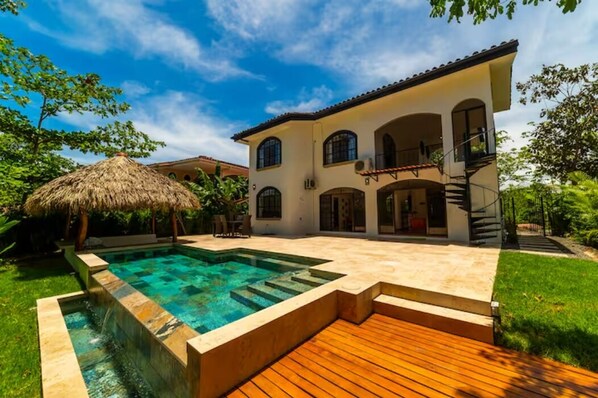 A two-story house with a swimming pool, a wooden deck, and a staircase leading to an upper level. - Casa 48· Poolside Relaxing Retreat Near the Beach (Esterillos Este)