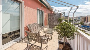 A balcony with wicker furniture, a potted plant, and a view of the cityscape. - Spacious 4BR Penthouse Updated Bathroom (Athens)