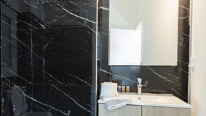 A modern bathroom with a black marble vanity, a wooden cabinet, and a mirror above the sink. - Hip And Fun in Athens Apt A (Athens)