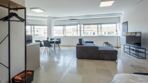 A spacious living area with a grey sofa, a dining table with chairs, and a kitchen area in the background. - Hip And Fun in Athens Apt A (Athens)