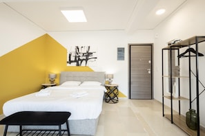 A modern hotel room with a bed, bedside tables, a bench, a wardrobe, and a painting on the wall. - Hip And Fun in Athens Apt A (Athens)