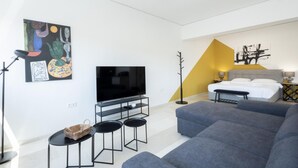 A modern living room with a flat-screen TV, grey sofas, a coffee table, and a painting on the wall. - Hip And Fun in Athens Apt A (Athens)