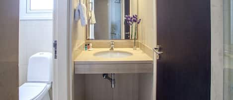 A small bathroom with a toilet, sink, and mirror.