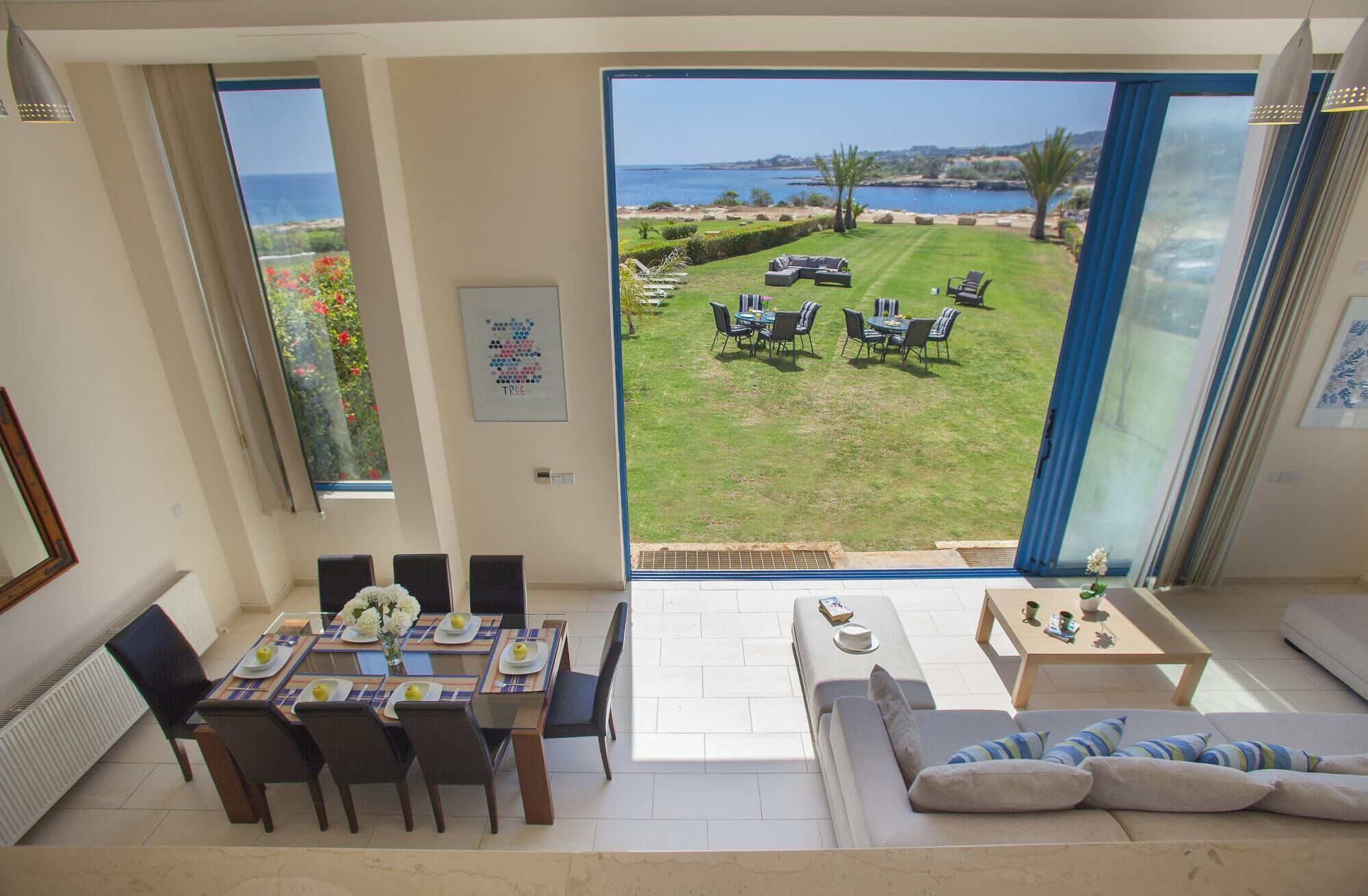 A spacious living area with a large sliding glass door leading to a private outdoor patio with a view of the sea.