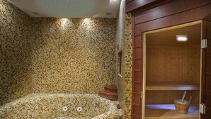A hot tub with mosaic tile walls, a wooden bench, and a wooden sauna room with a bucket and brush. - Villa Infinite Aretousa (Paralimni)