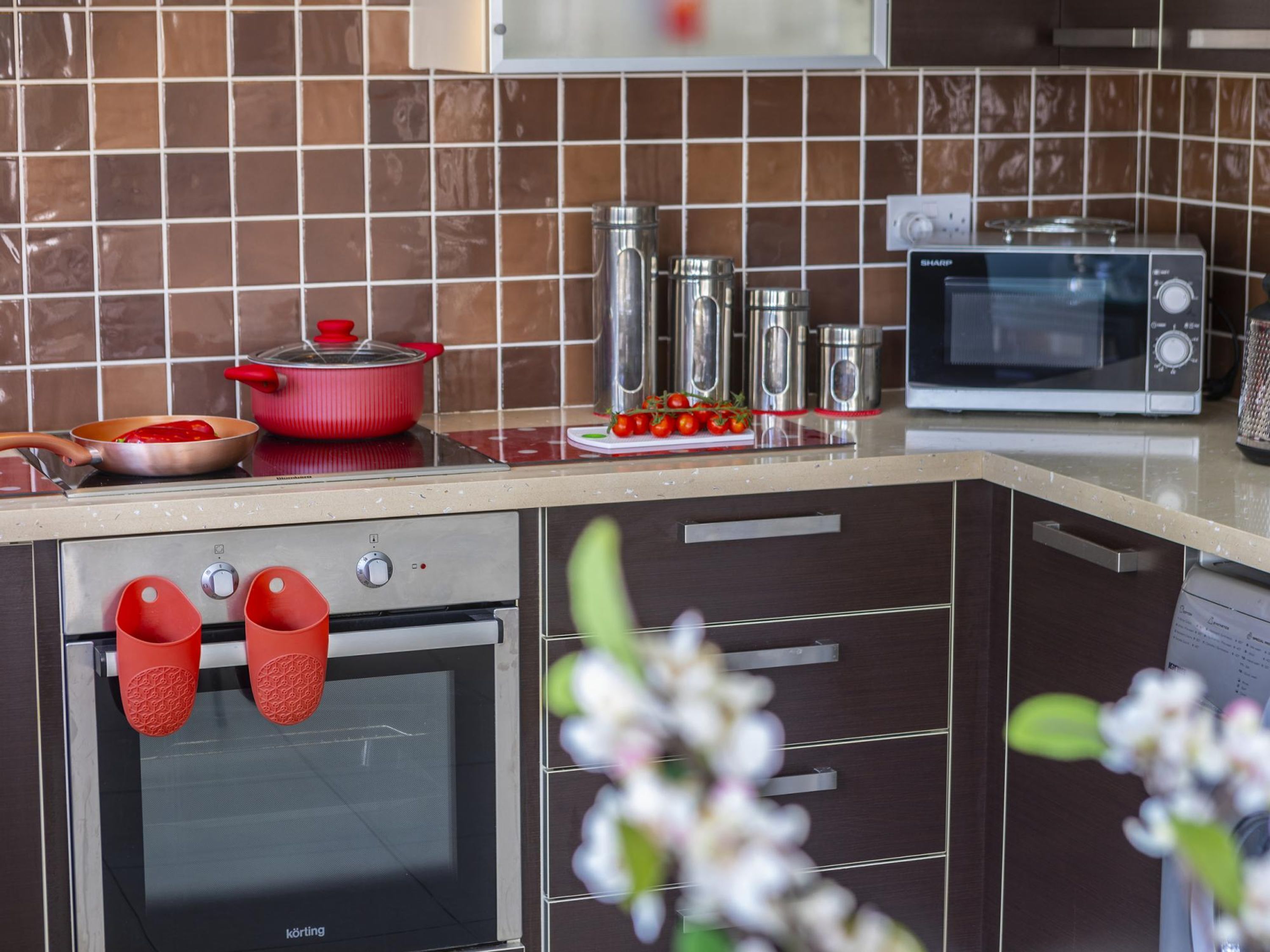 A kitchen with a microwave, oven, and red pot on the counter.