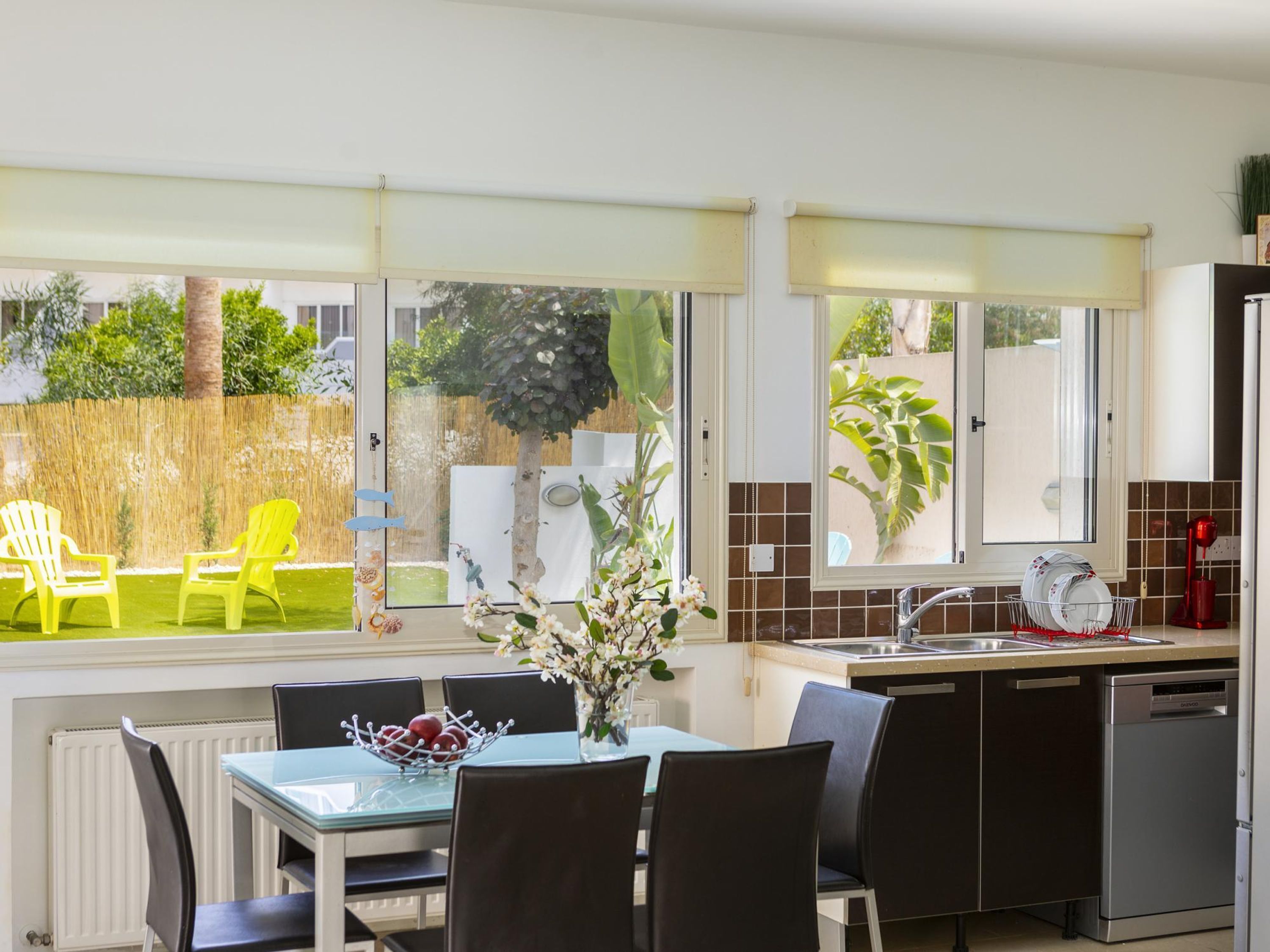 A modern kitchen with a dining area, large windows, and a view of the outdoors.