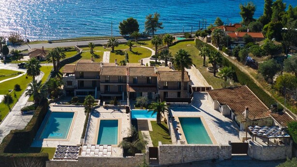 A large villa with multiple swimming pools, a well-maintained garden, and a view of the sea. - Palmrise Luxury Villas - Thea Villa (Kassandra)