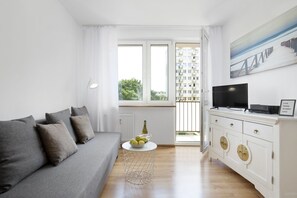 Relax in a bright and airy space with a comfortable sofa, flat-screen TV, and a view of lush greenery.