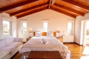 Relax in this serene bedroom with a large bed, bedside tables, and a wooden bench.