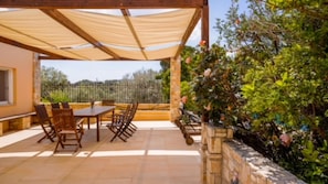 Relax in a serene outdoor space with a shaded patio, perfect for dining or socializing amidst lush greenery and a peaceful atmosphere.