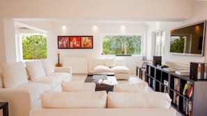 Relax in this stylish living room with a sofa, coffee table, and bookshelf, surrounded by a peaceful view of the outdoors.