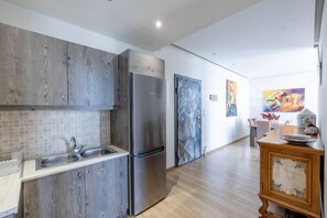 Enjoy a meal at the dining table, surrounded by abstract artwork in this kitchen with a sink and refrigerator.