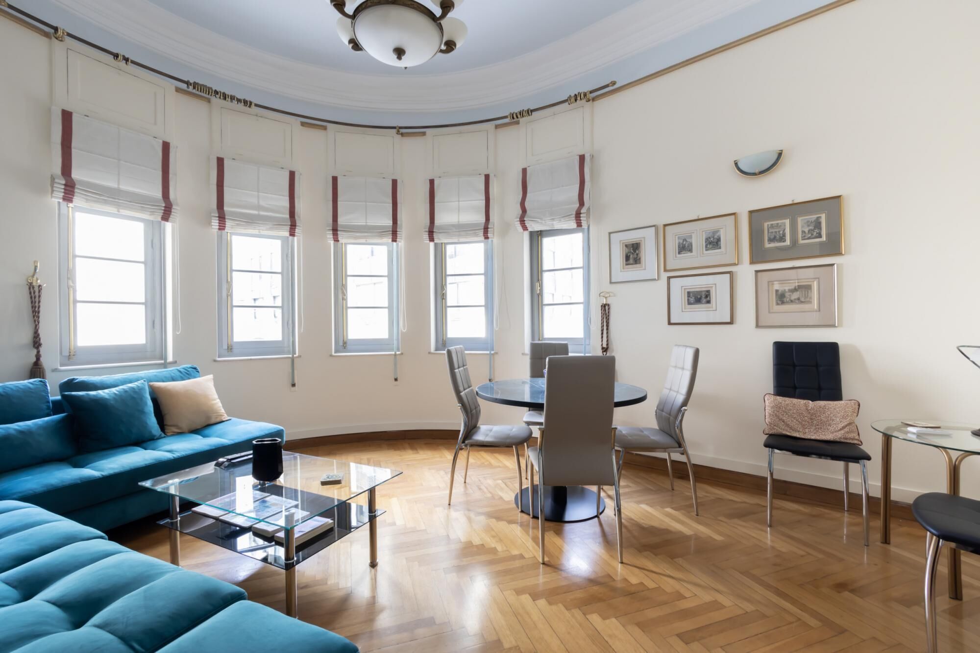 Un salon spacieux avec un canapé bleu, une table basse en verre et un coin repas comprenant des chaises et une table.