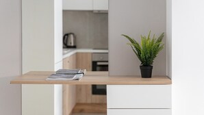 Een klein houten tafeltje met een kamerplant varens en enkele tijdschriften.