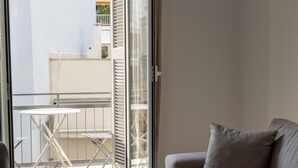 Een balkon met een tafel en stoelen, een grijze bank en een schuifdeur van glas.
