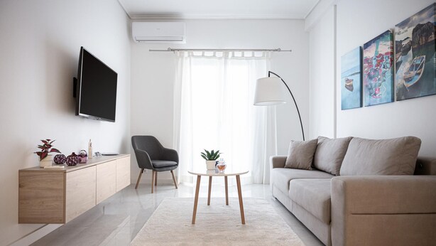 Een moderne woonkamer met een flatscreen televisie, een bank, een fauteuil, een salontafel en een kast.