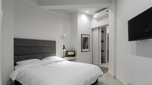 A modern bedroom with a large bed, a bedside table with a lamp, a flat-screen TV, and a walk-in closet. - 85 sqm in the Heart of Athens w Rooftop Deck (Athens)