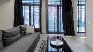 A modern living room with a grey sofa, black curtains, and a patterned rug. - 85 sqm in the Heart of Athens w Rooftop Deck (Athens)