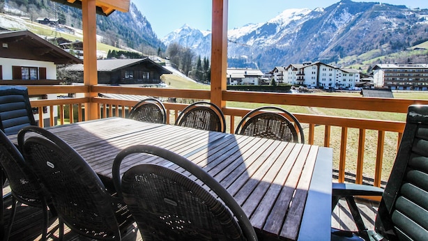 A wooden deck with a table and chairs, overlooking a mountainous landscape with buildings in the background. - Tauern Relax Lodges - Garden (Kaprun)