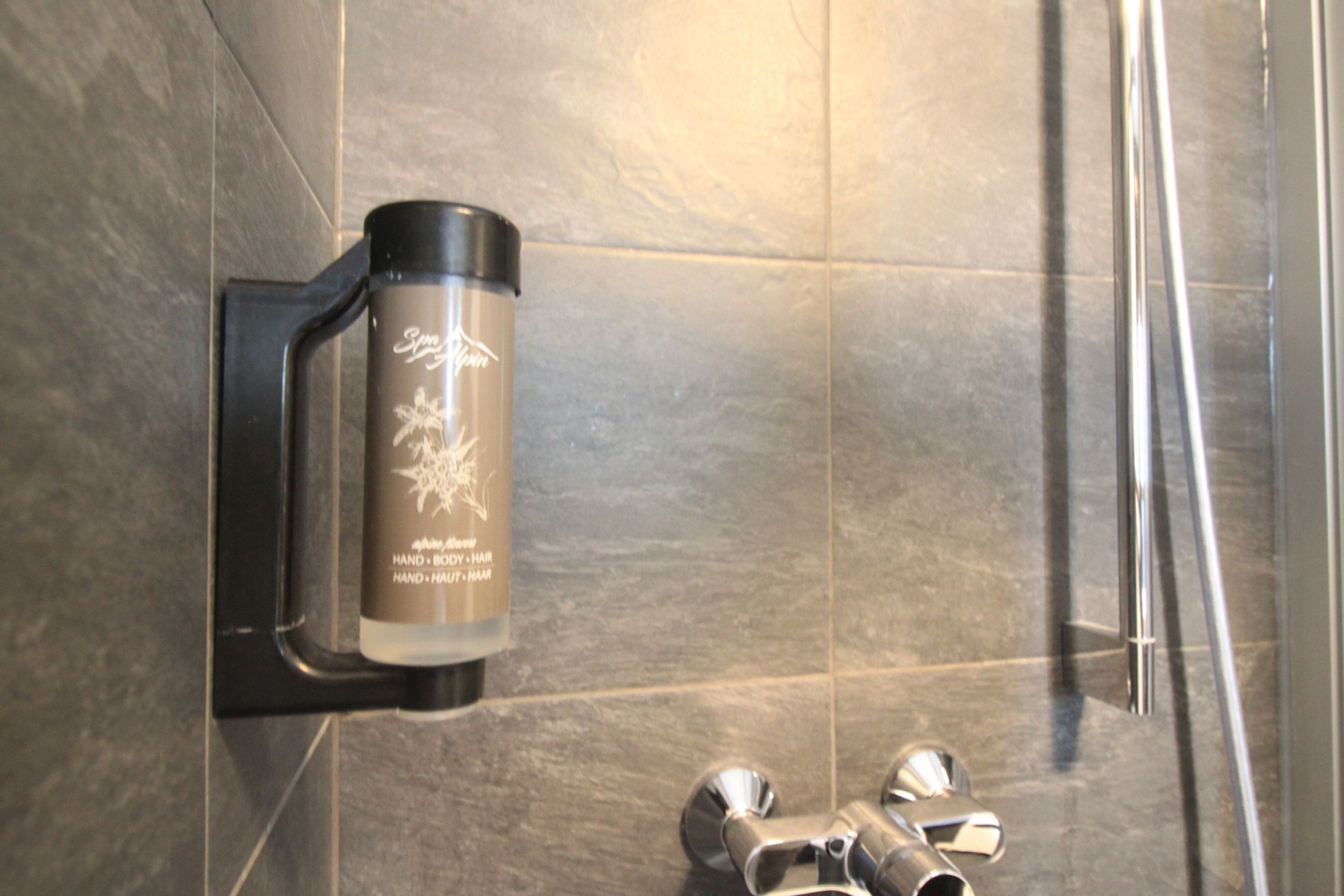 A shower with a hand soap dispenser mounted on the wall.