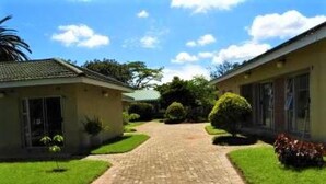 A pathway leading to a building with a tiled roof, surrounded by well-maintained grass and small plants. - 2 Bedroomed Apartment With En-suite and Kitchenette - 2066 (Harare)