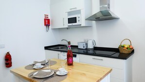 A small kitchenette with a microwave, toaster, kettle, and a basket of fruit on the counter. - Ribeira das Casas Apt 2C by Homie (Funchal)