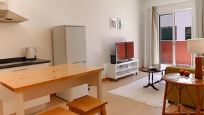 A compact living space with a kitchenette, a dining area, a TV, and a small seating area with a table and chair. - Ribeira das Casas Apt 2C by Homie (Funchal)