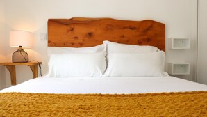 A bed with white linens, a wooden headboard, and a mustard-colored throw blanket. - Ribeira das Casas Apt 2C by Homie (Funchal)