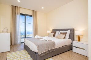 Relax in a spacious room with a large bed, bedside tables, and a balcony with a window offering a view.
