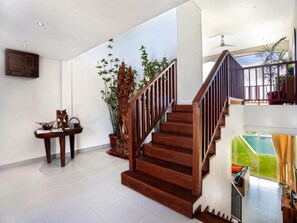Staircase leads to a balcony with a view of the pool and lush surroundings.