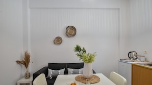 A modern dining area with a white table, chairs, and a decorative vase with green plants. - Apartments for 3 2nd Floor (Malevizi)