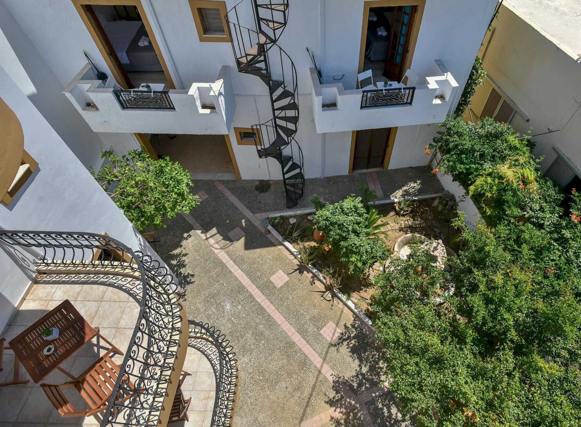 Une cour intérieure agrémentée d’un escalier en colimaçon, de plantes en pot et de sièges d’extérieur.