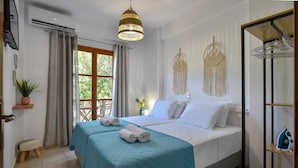 A hotel room with a bed, a hanging light fixture, a plant, and a view of the outdoors. - Apartments for 3 2nd Floor (Malevizi)