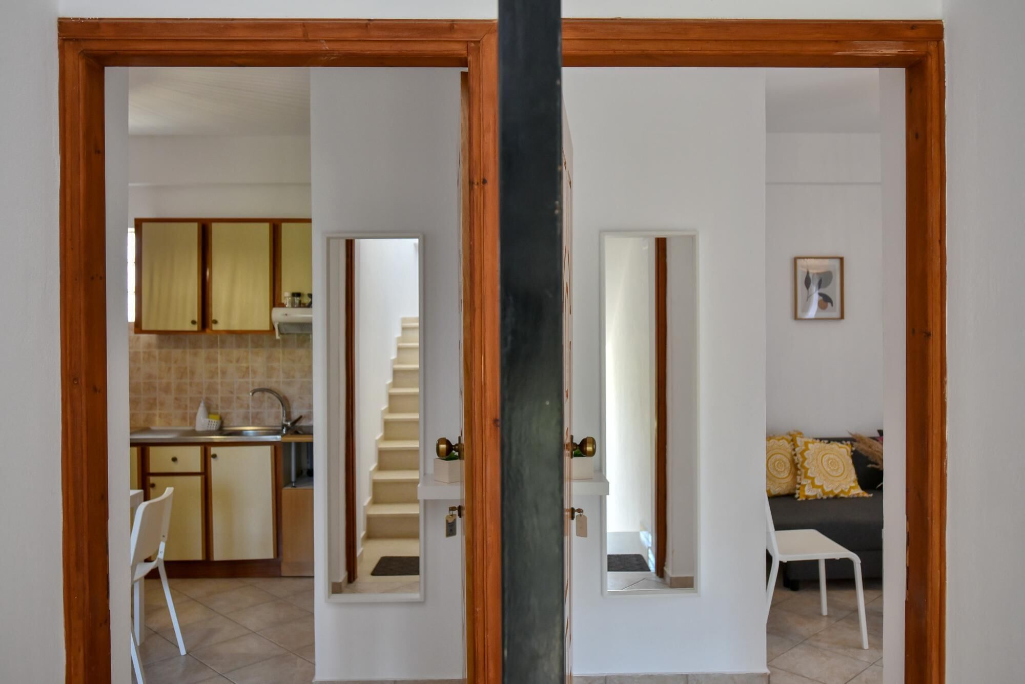 A view through a doorway into a living area with a sofa and a dining area with a staircase.