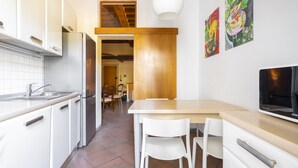 A modern kitchen with white cabinets, a stainless steel refrigerator, and a wooden dining table with white chairs. - Verdi 11 - Two Bedroom Apartment, Sleeps 4 (Firenze)