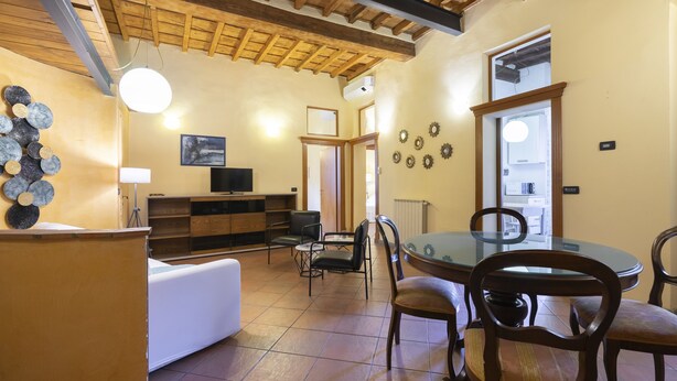 A spacious dining area with a round glass table and wooden chairs, a white sofa, and a wooden cabinet. - Verdi 11 - Two Bedroom Apartment, Sleeps 4 (Firenze)