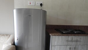 Een keuken met een roestvrijstalen koelkast, een aanrecht met een kookplaat en een kast met twee handgrepen.