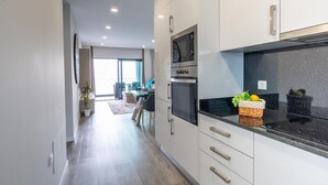 Una cocina moderna con armarios blancos, encimera negra y horno empotrado.