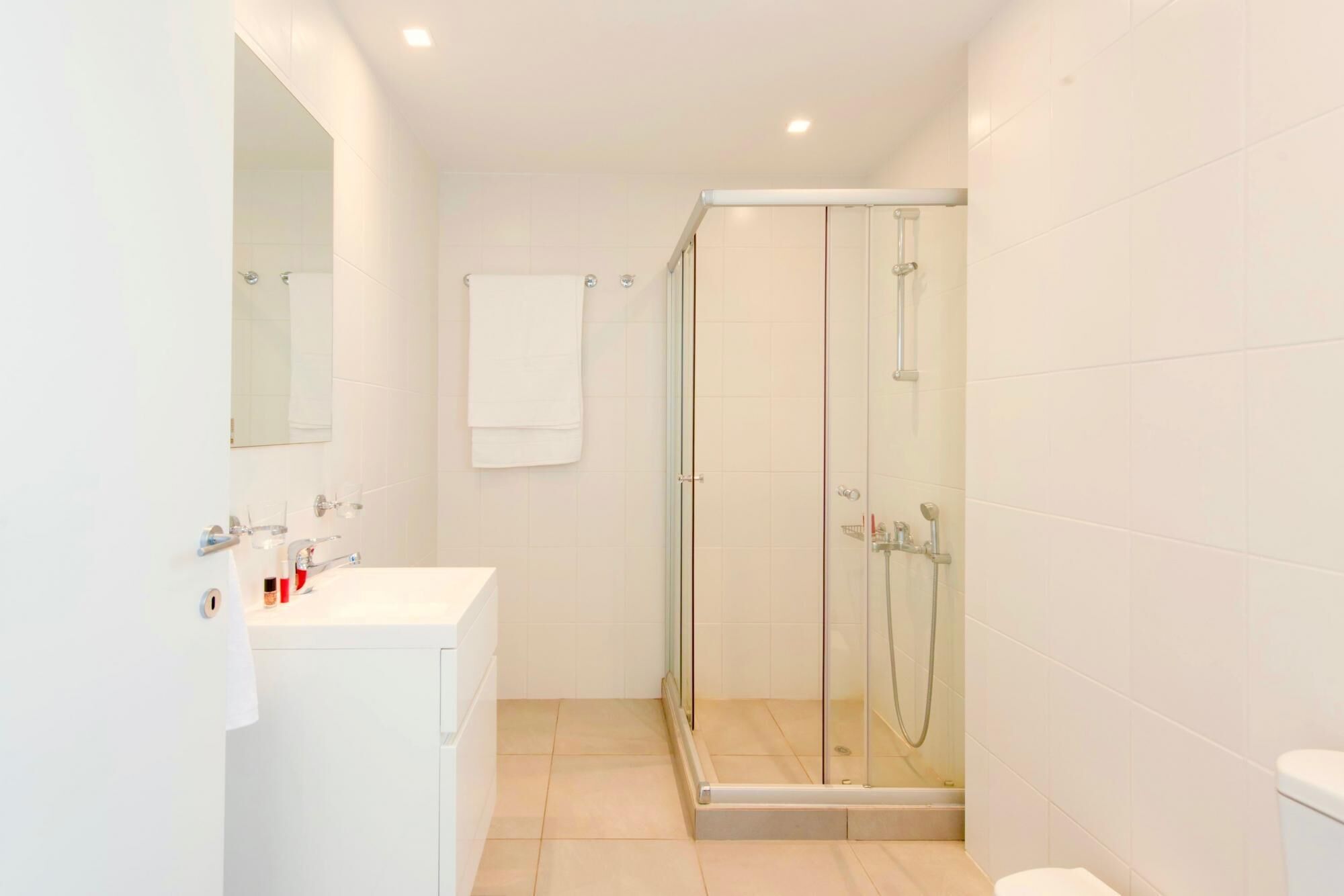 A modern bathroom with a glass-enclosed shower, a white sink with a mirror, and a toilet.