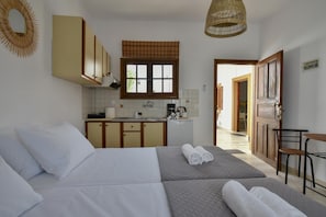 Cozy retreat with a large bed, kitchenette, and comfortable chair.