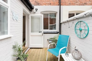 Enjoy a peaceful retreat with an outdoor space featuring a door to an adjacent room, a chair, and a small table.
