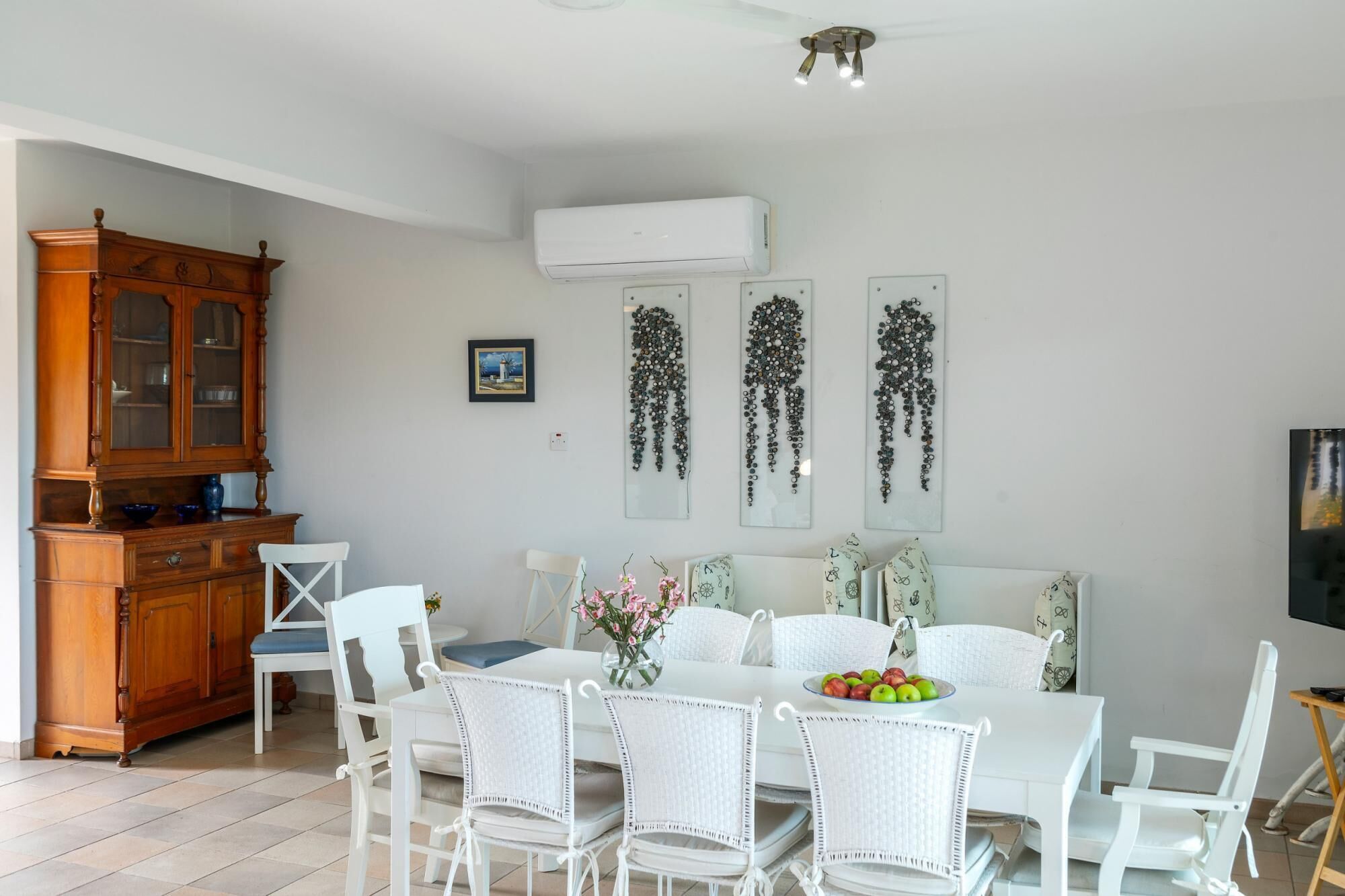 Un comedor con una mesa blanca, sillas blancas y un armario de madera.