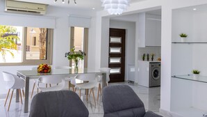 Een moderne keuken met witte kastjes, een ingebouwde wasmachine en een glazen plank met planten.