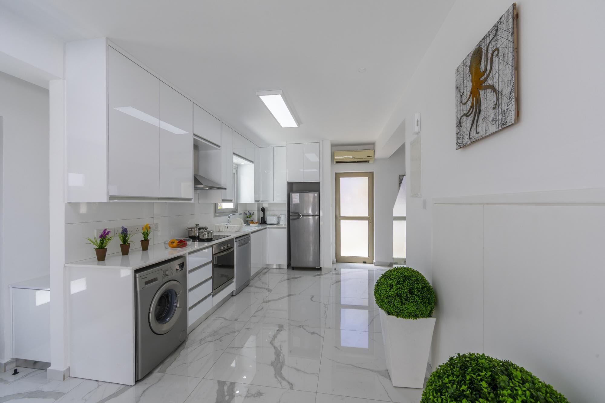 A modern kitchen with white cabinetry, a stainless steel refrigerator, and a washing machine.