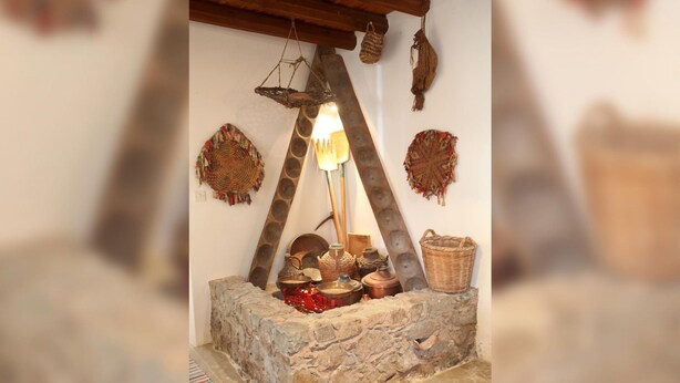 Un pozo de piedra rústico con una escalera de madera, rodeado de cestas tejidas y cerámica.