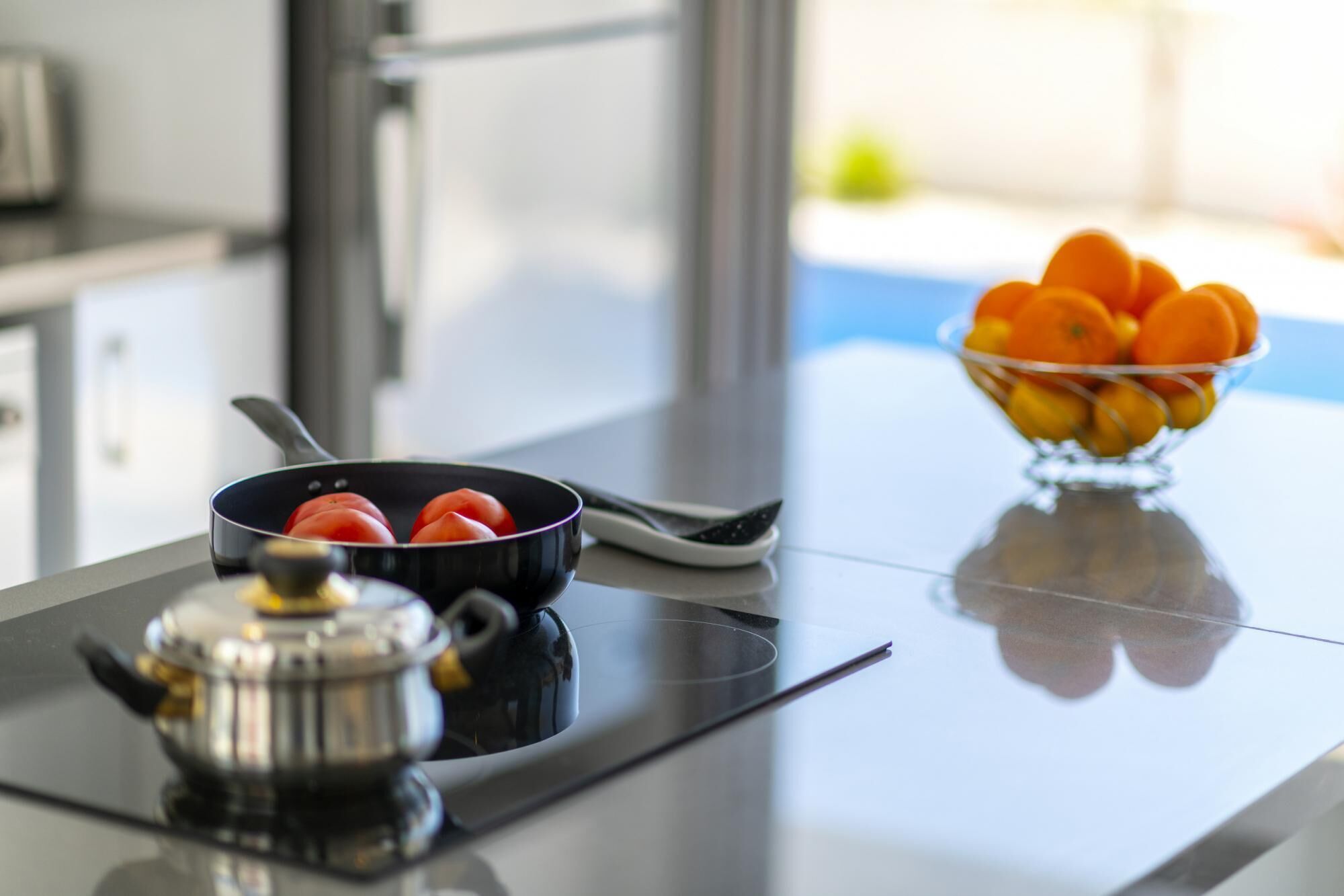 Un plan de travail de cuisine avec une poêle, une casserole et un saladier rempli de fruits.